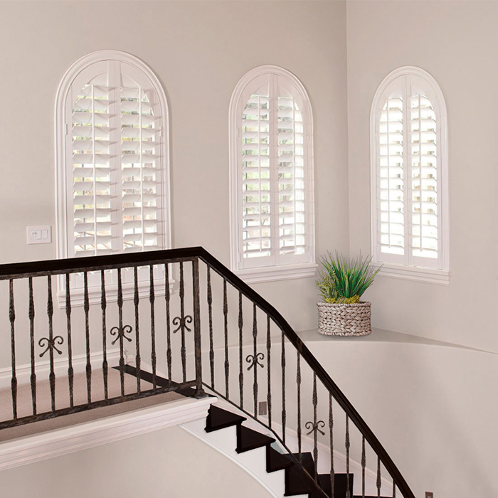 White arched shutter windows by a stairwell.