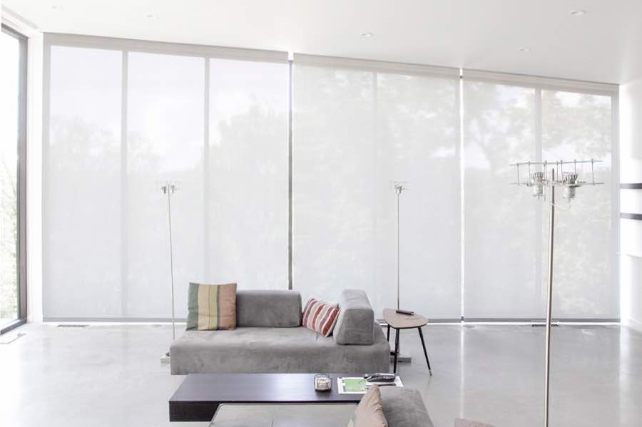 White motorized shades on a wall of tall great room windows