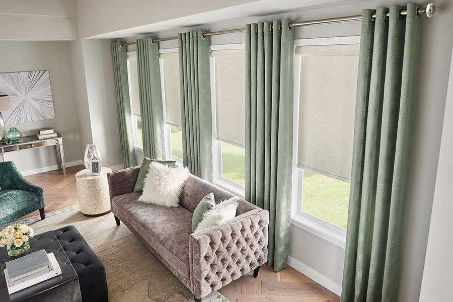Customize your living room windows with elegant white roller shades White roller shades paired with green curtains in a living room