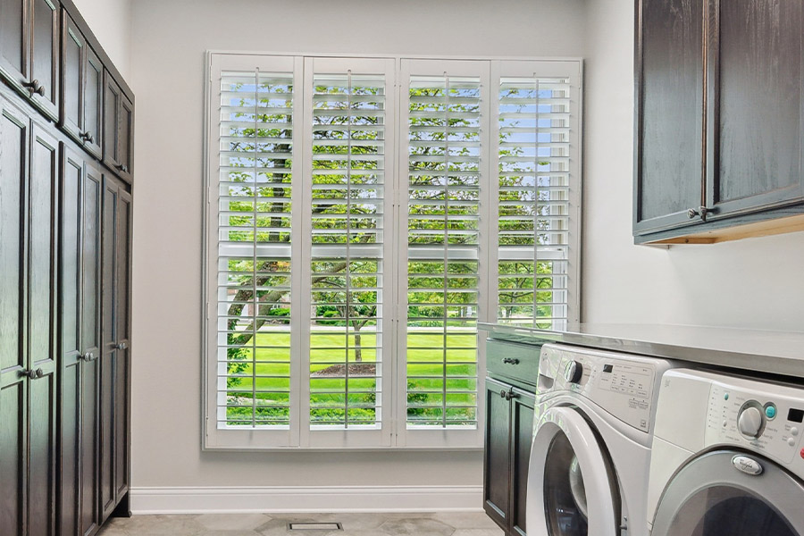 Find the perfect level of natural light for your San Jose laundry room with interior shutters. White Polywood shutters letting light through a laundry room window
