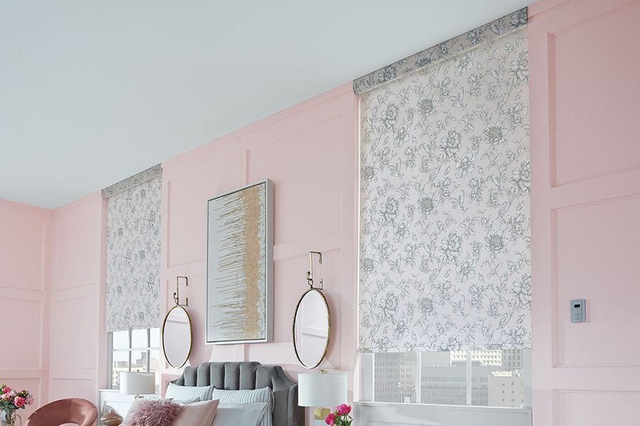 Patterned roller shades add a finishing touch to any room. Gray floral roller shades in a pink bedroom